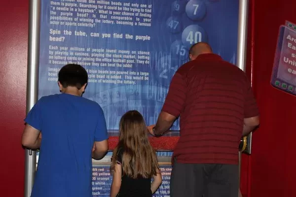 find-the-bead Family looking for the purple bead in the Find the Bead exhibit at WonderWorks Orlando.