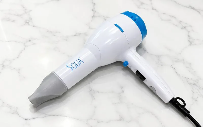 Original Solia hair dryer with concentrator nozzle attached on a white marble countertop.