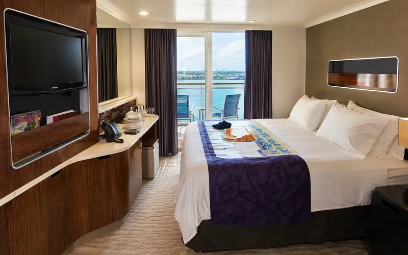 Norwegian Getaway balcony stateroom with a king-size bed, wood cabinetry, and private balcony overlooking the water