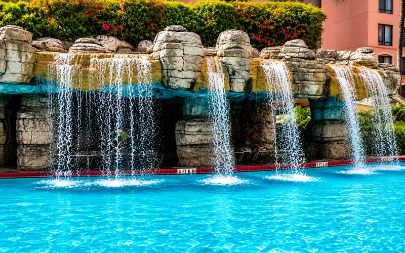 Tropical waterfall surrounded by rock formations and lush landscaping at the Caribe Royale Orlando pool.