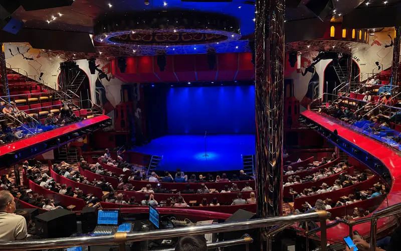 Families laughing during a comedy performance in a cruise ship lounge.