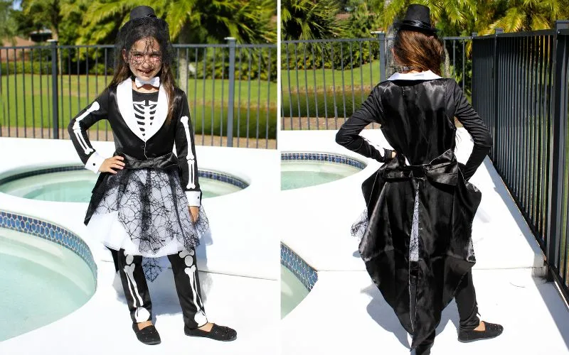 Side-by-side view of a girl wearing a black-and-white skeleton costume from the front and back with a top hat, veil, spiderweb skirt, and long satin tails