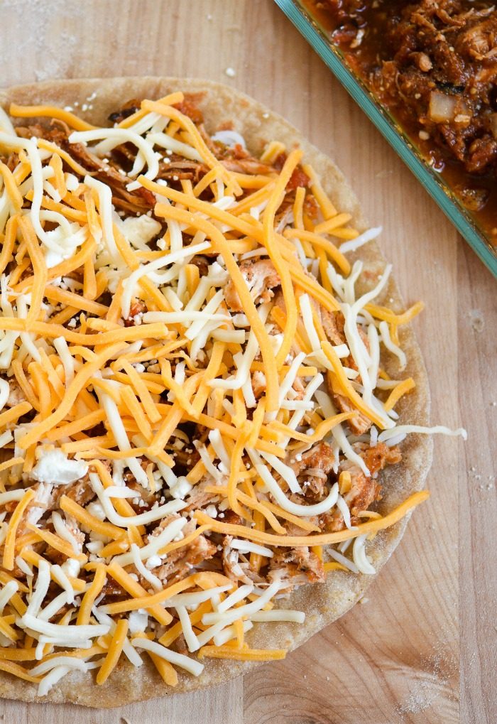Rotisserie chicken quesadilla being prepared with shredded cheese and seasoned chicken on a tortilla.