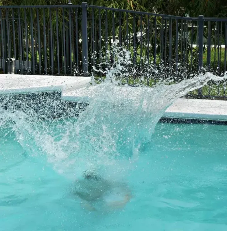 Large splash in a backyard swimming pool after a cannonball jump