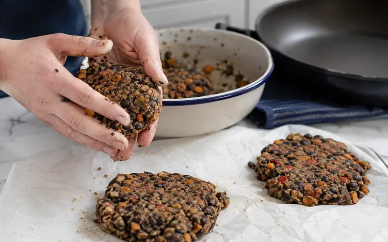Shaping black bean and vegetable burger patties before chilling and skillet cooking.