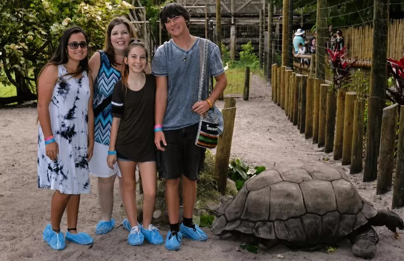Family standing near an Aldabra tortoise at the Palm Beach Zoo