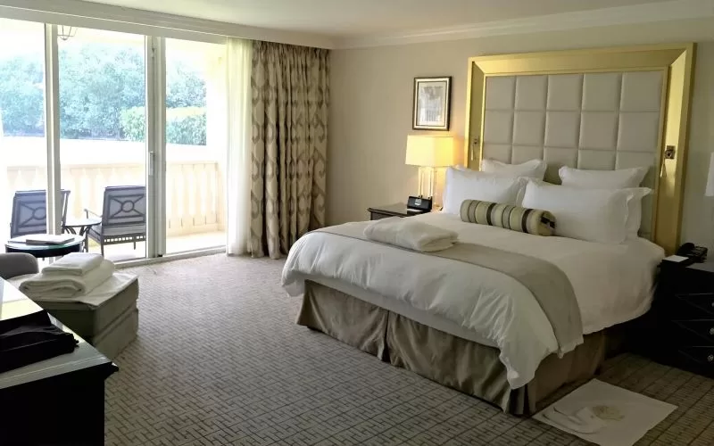Bedroom inside the Trump Doral villas with a king bed, terrace doors, seating area, and neutral decor.