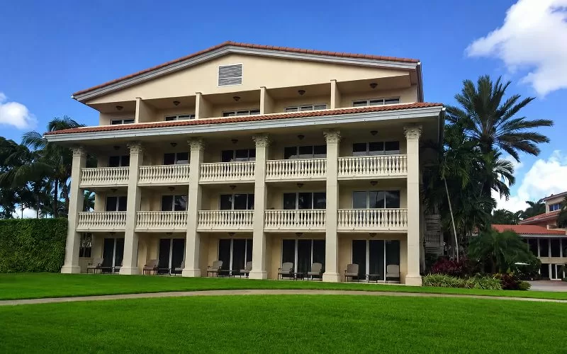 Exterior view of the Trump Doral villas with green lawn, palm trees, and Mediterranean-style balconies.