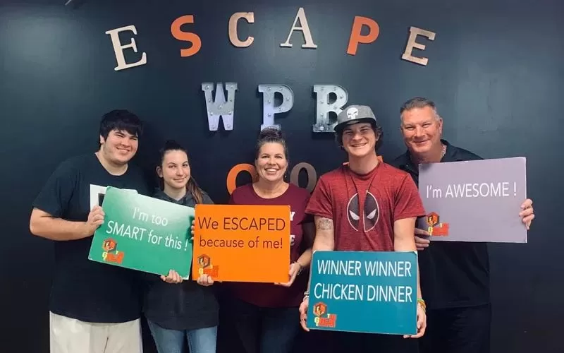 Family holding escape room signs after completing an escape room at West Palm Beach Escape Rooms