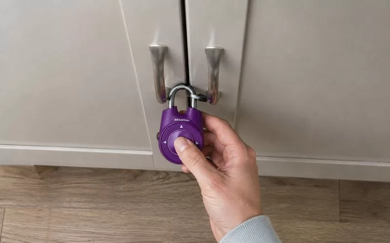 Hand opening a purple combination lock on a cabinet during an escape room style puzzle