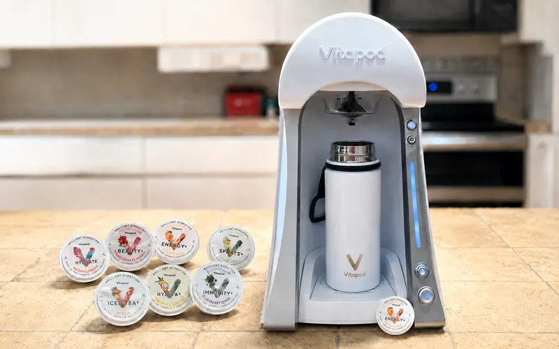 Vitapod drink machine with reusable bottle and assorted flavored drink pods on a kitchen counter