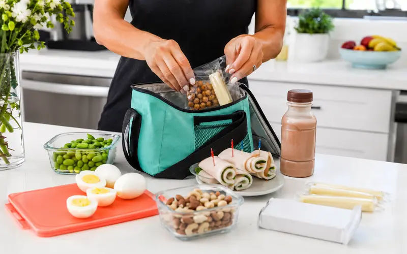 High-protein snacks being packed into a reusable lunch bag.