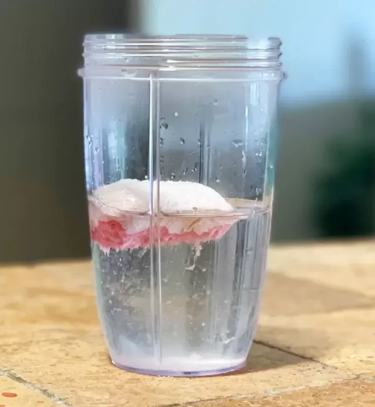 VADE strawberry protein pack dissolving in water inside a clear blender cup