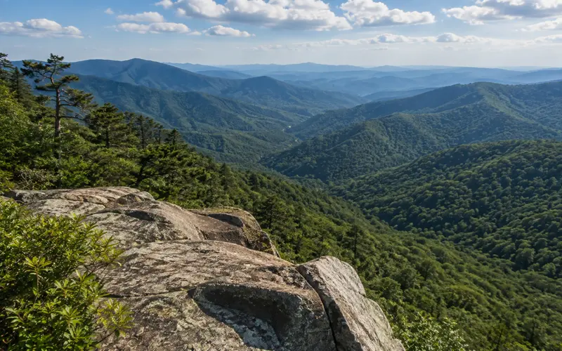 Rocky mountain overlook above a forested valley and distant Blue Ridge ridges