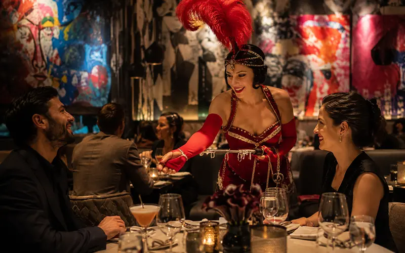 Live performer entertaining diners inside a colorful upscale Las Vegas restaurant with cocktails and contemporary artwork.
