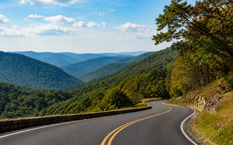 Winding mountain road through forested Pennsylvania hills with layered Appalachian ridges in the distance.