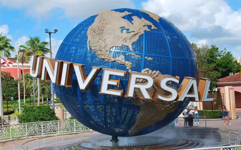Universal Orlando globe entrance with palm trees and guests arriving at the theme park.