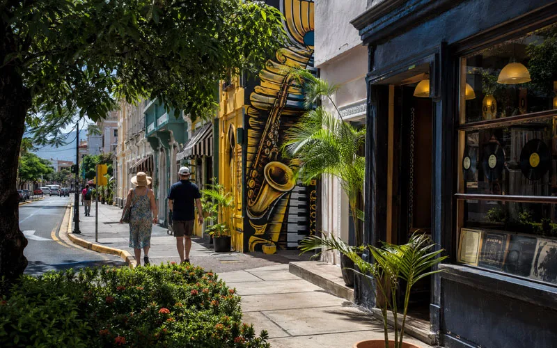 Visitors walking past music-inspired street art and a record shop in Kingston, Jamaica