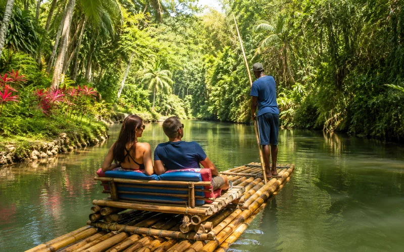 Travelers riding a bamboo raft along the Martha Brae River in Jamaica