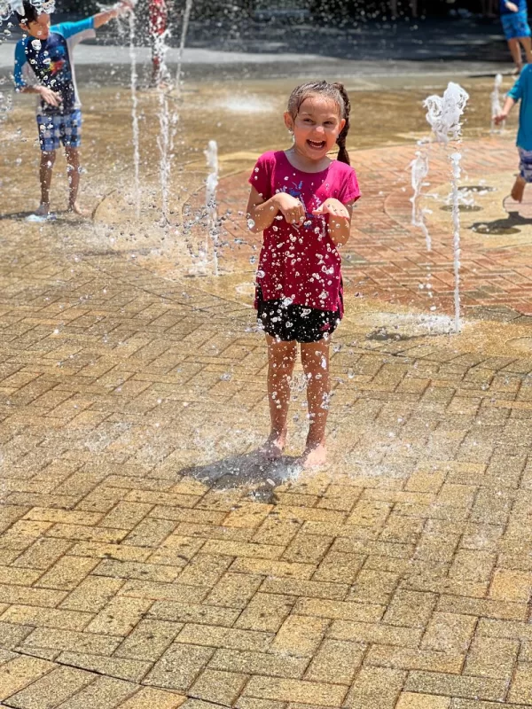Child smiling while playing in the splash pad at the Palm Beach Zoo.