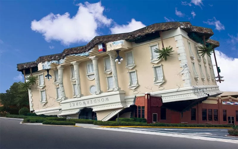 Upside-down WonderWorks Orlando building with a bright blue sky and clouds.