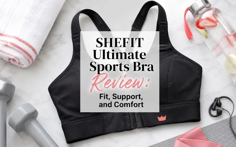 Black high-impact sports bra surrounded by gray dumbbells, a rolled towel, water bottle, and workout accessories with the title “SHEFIT Ultimate Sports Bra Review: Fit, Support, and Comfort.”