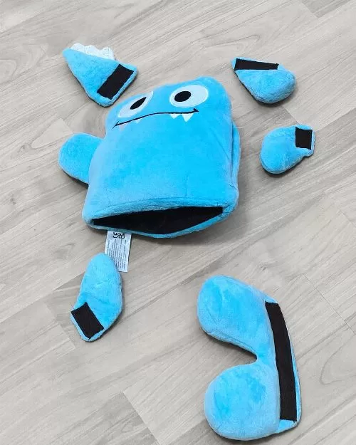 Blue Tearribles dog toy taken apart on a light gray floor with the detachable pieces spread around it.