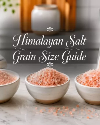 Bowls of different pink Himalayan salt grain sizes with a salt grinder on a bright kitchen counter.