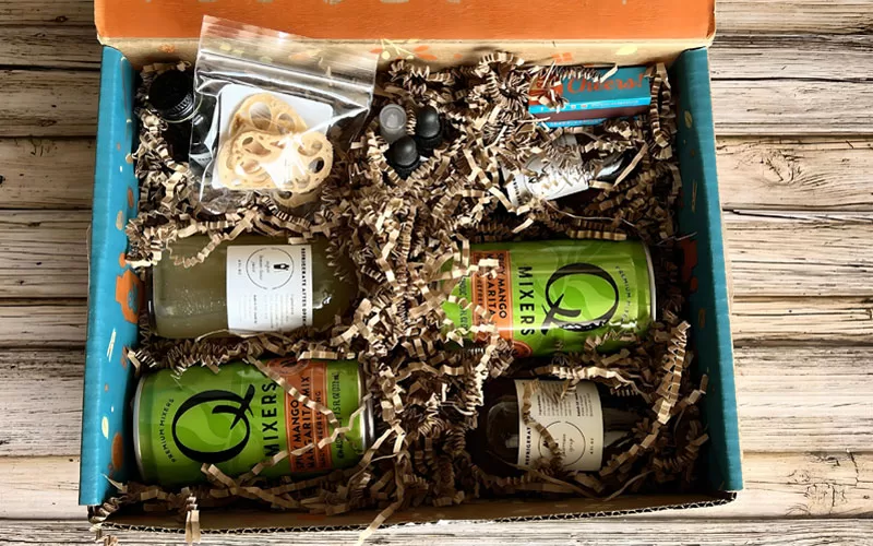 Open Shaker & Spoon cocktail subscription box with mixers, garnishes, and drink ingredients inside