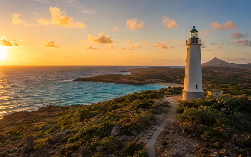 White lighthouse overlooking the Aruba coastline at sunset.
