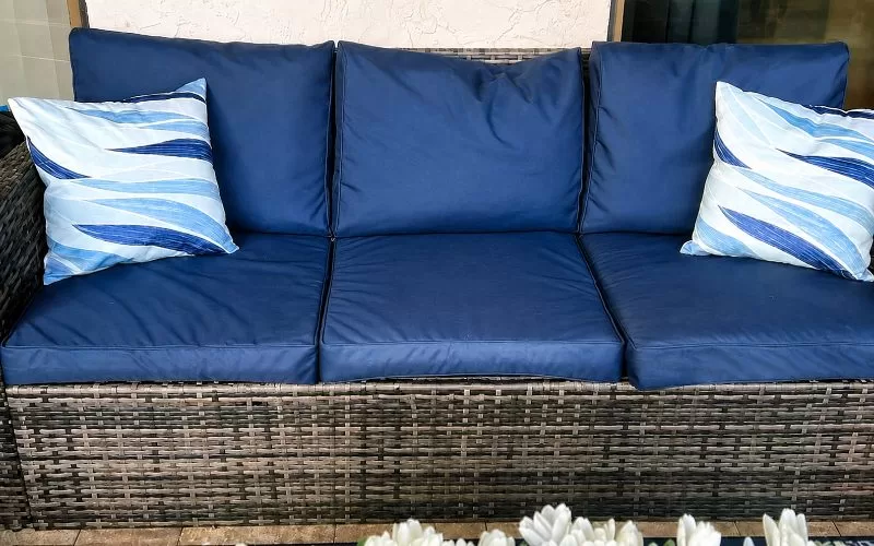 Navy custom patio cushion covers on a dark wicker outdoor sofa with blue and white accent pillows