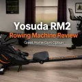 Yosuda RM2 rowing machine review featured image showing a compact rowing machine in a home gym workout room with fitness equipment and motivational wall decor.
