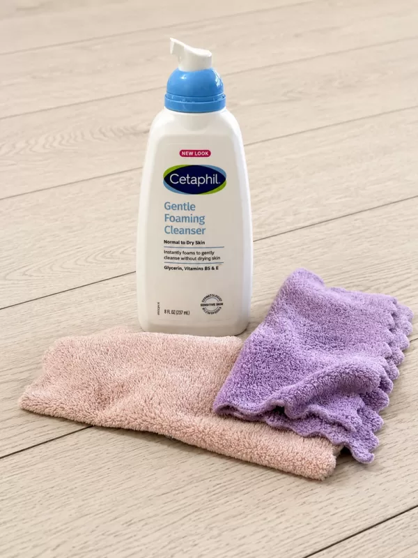 Cetaphil Gentle Foaming Cleanser with soft facial washcloths on a light wood background for a mature skincare routine.