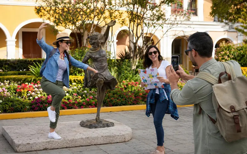 Adult travelers complete a funny photo challenge by recreating the pose of a statue.